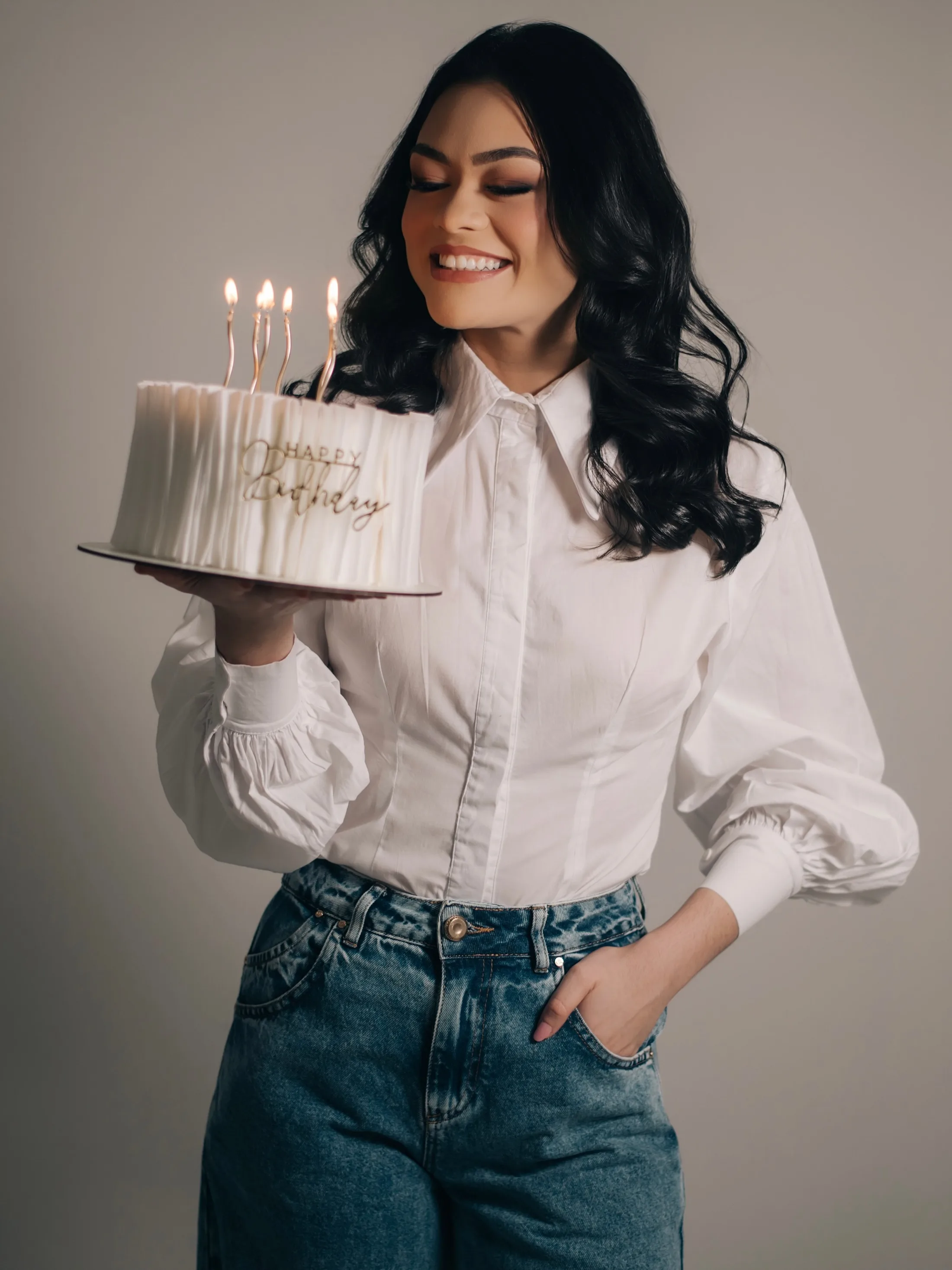 Mulher sorrindo com bolo de aniversário nas mãos