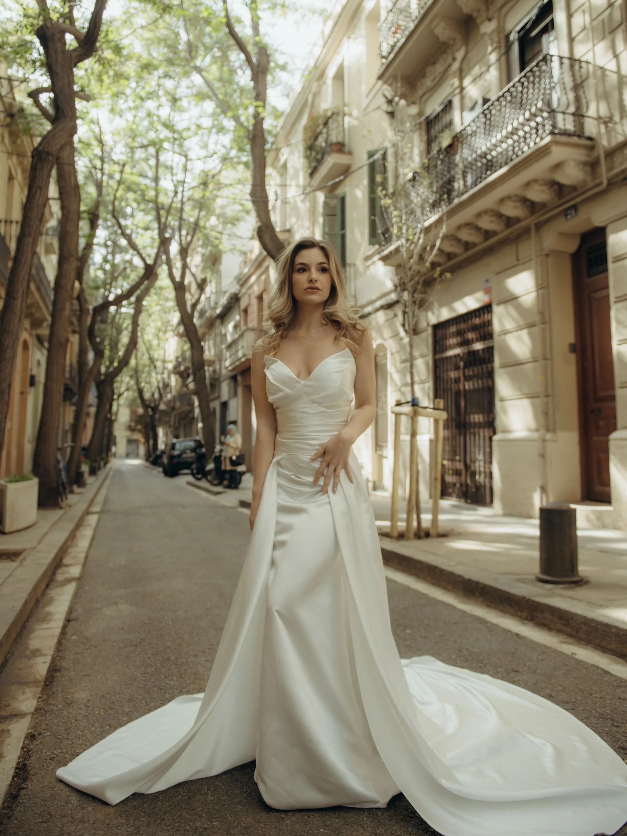 Noiva em rua arborizada com arquitetura ao fundo