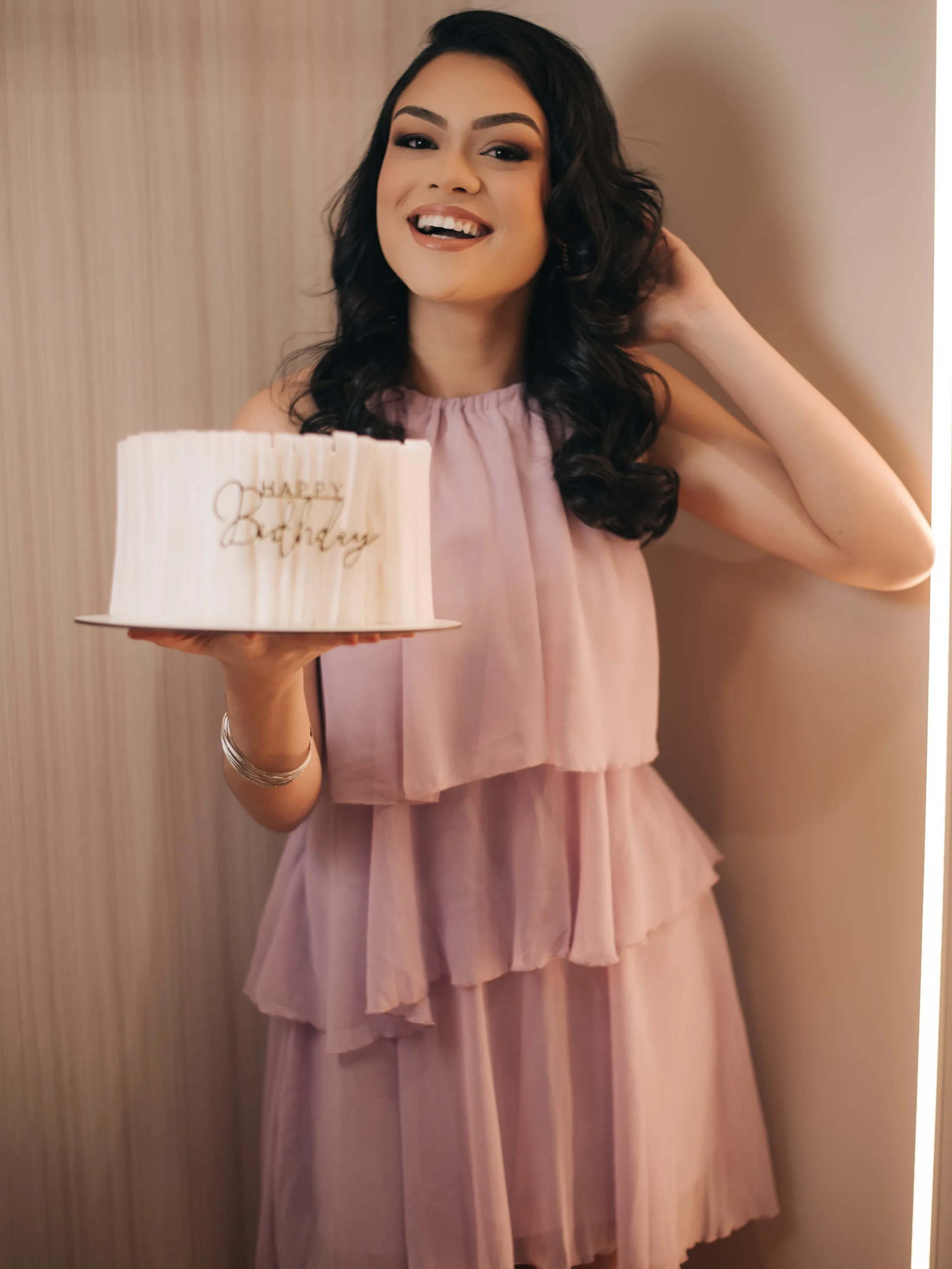 Mulher com roupa rosa segurando bolo de aniversário