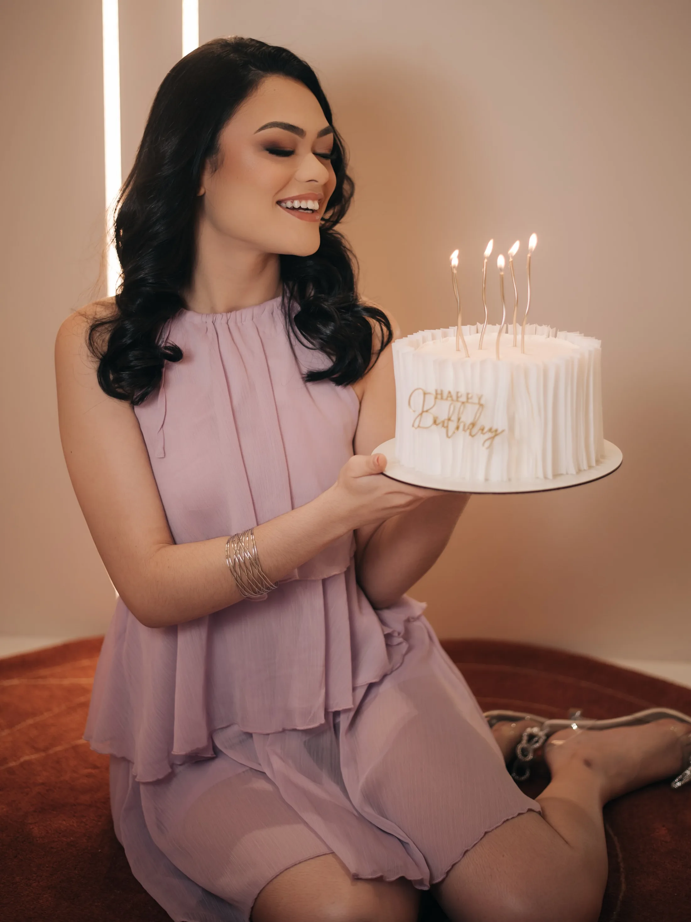 Mulher sentada com bolo de aniversário nas mãos