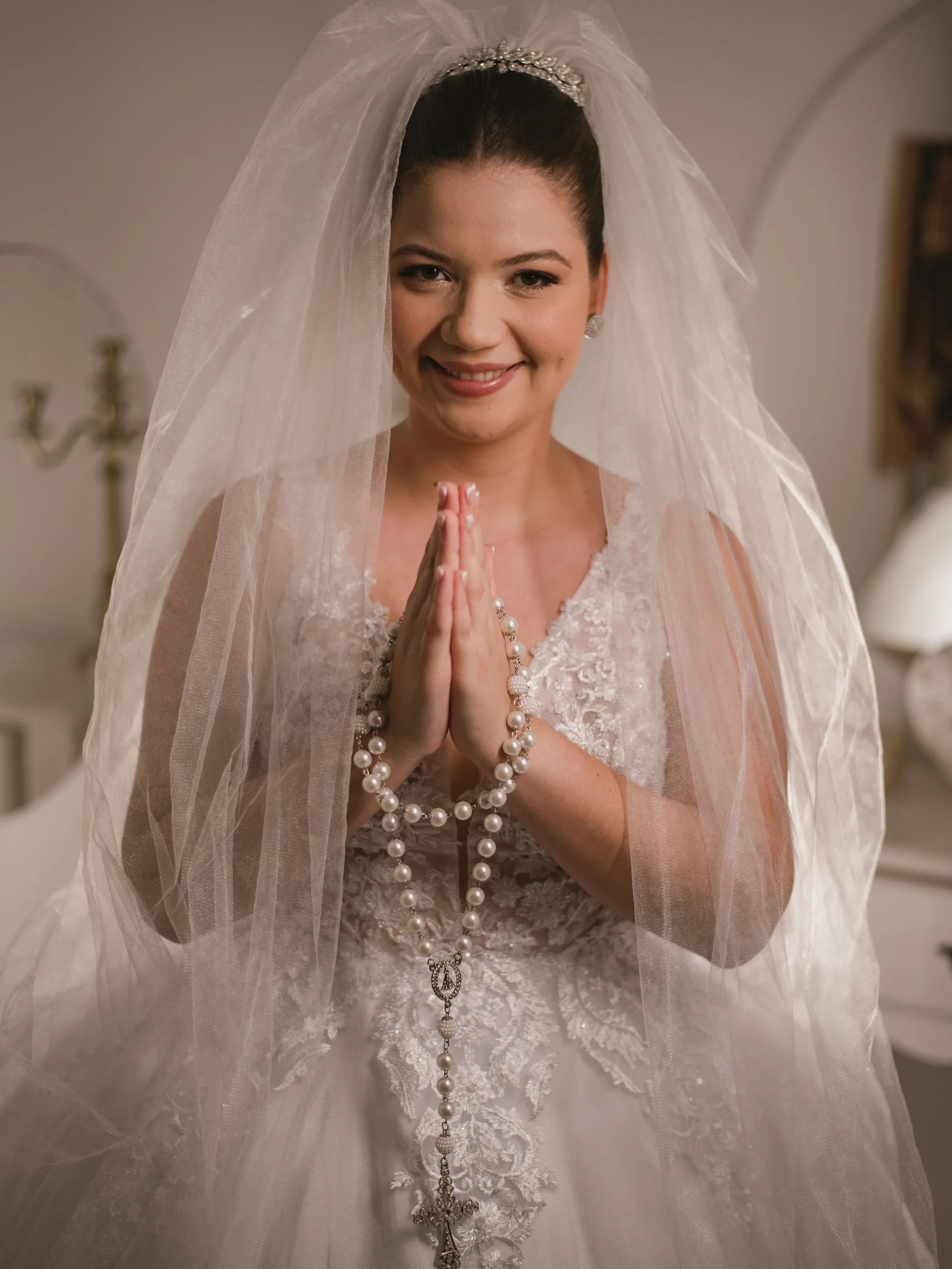 Noiva sorrindo com as mãos unidas sob o véu